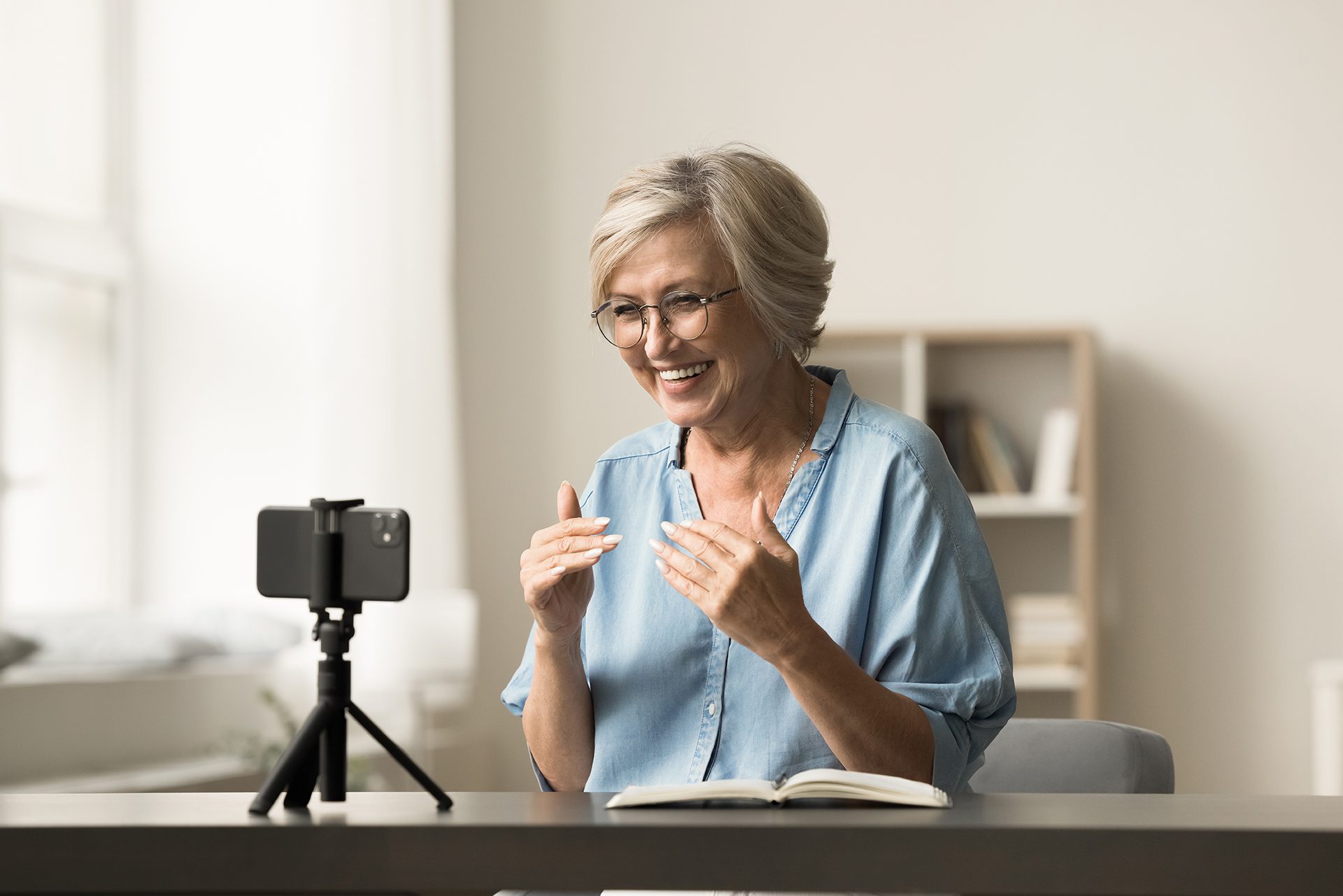 3 A woman is sitting at her desk with a book and phone.
