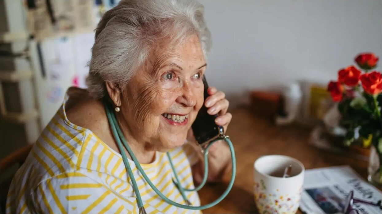 Elderly woman smiling and talking on phone.