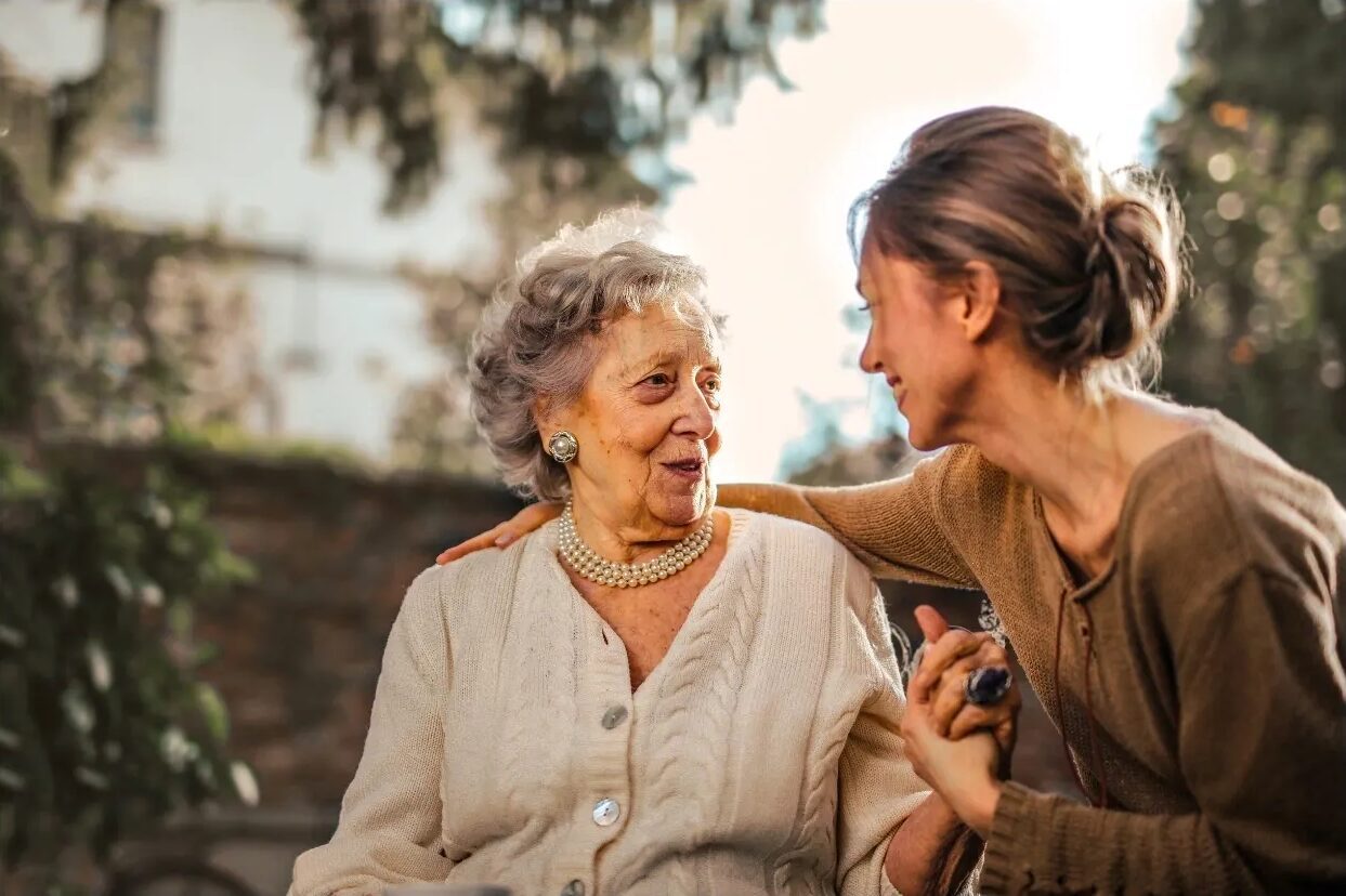 Elderly woman and younger woman smiling together.