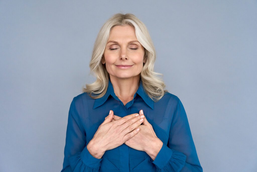 Smiling woman with hands on chest.